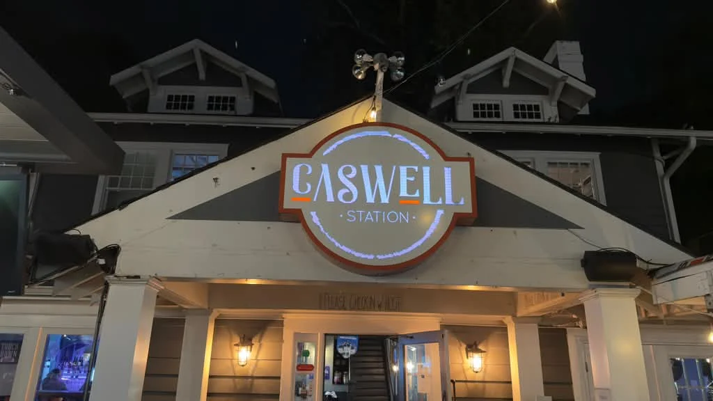 Caswell Station’s illuminated sign and warmly lit entrance at night in Charlotte