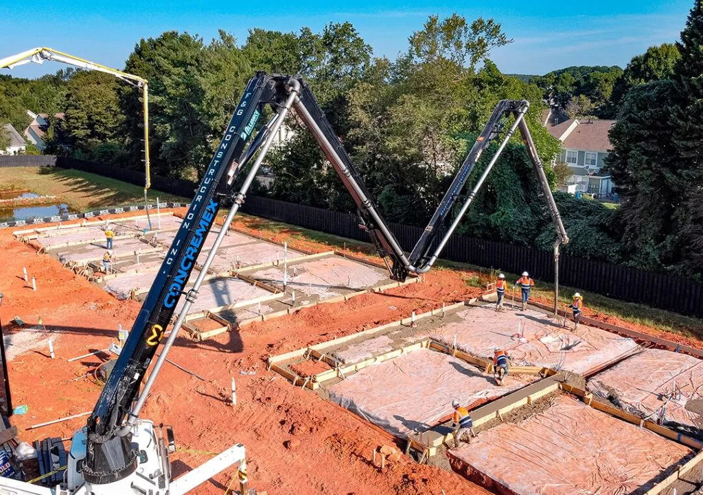 Concremex concrete pump reaching across foundations at an outdoor construction project