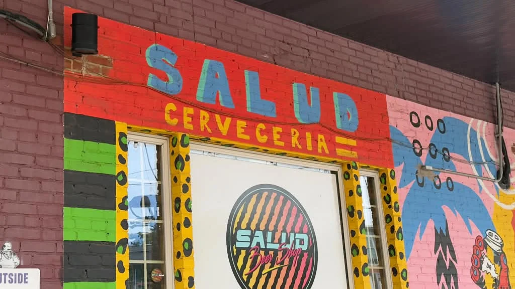 The colorful Salud Cervecería storefront in NoDa, with its red sign and painted mural